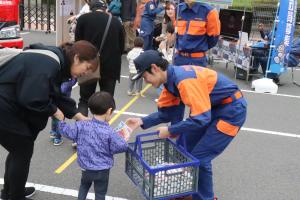 子どもたちに消防団広報グッズを渡している